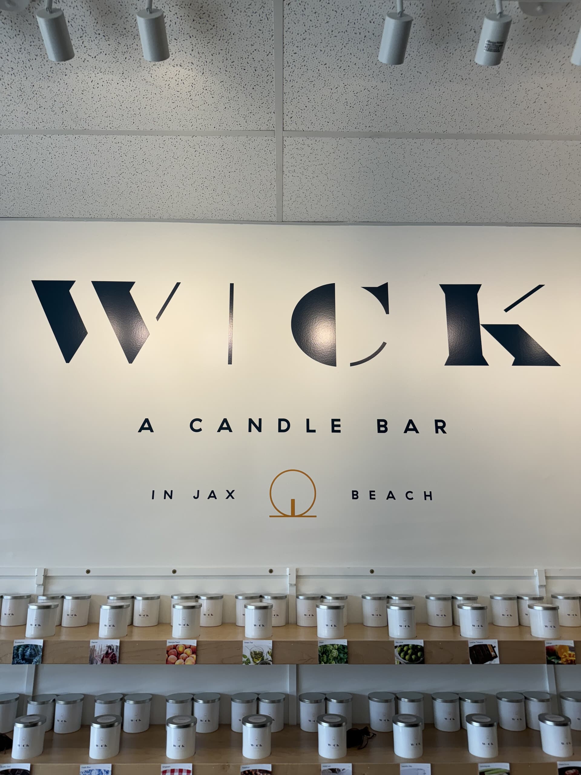 Wick candle bar logo wall and sample tins at Jax Beach