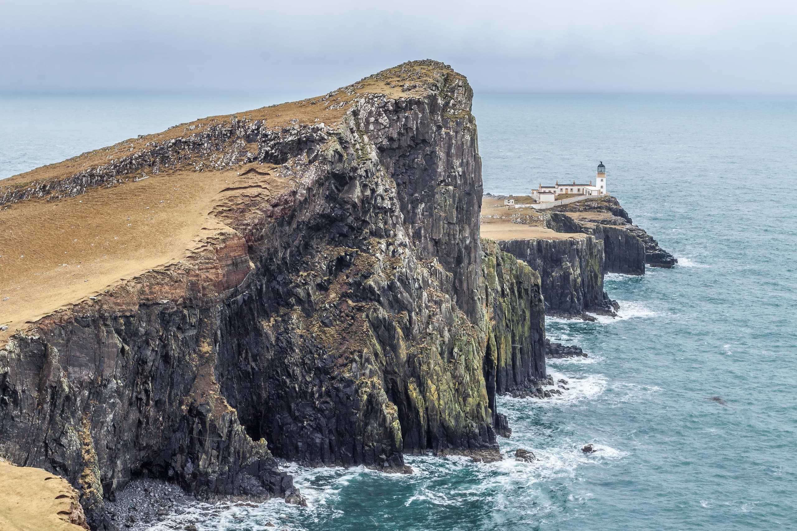 Sea cliffs and lighthouse on rugged Atlantic coast, dramatic view