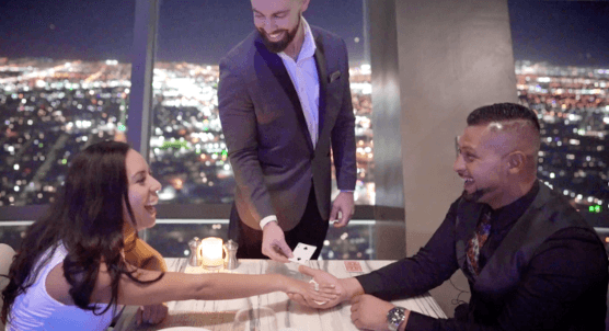 Man proposing at rooftop restaurant overlooking city skyline at night