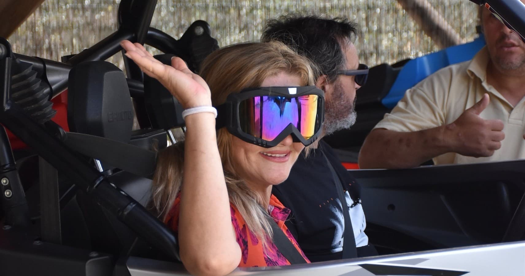 Smiling passenger wearing goggles inside off-road buggy on tour
