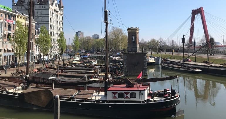 Historic harbor boats moored near Rotterdam waterfront and bridge