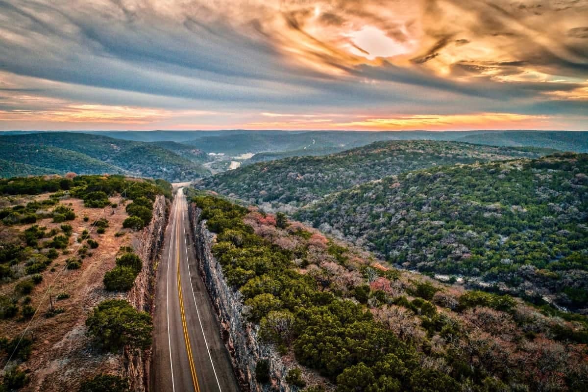 Scenic winding mountain road with dramatic sunset skies