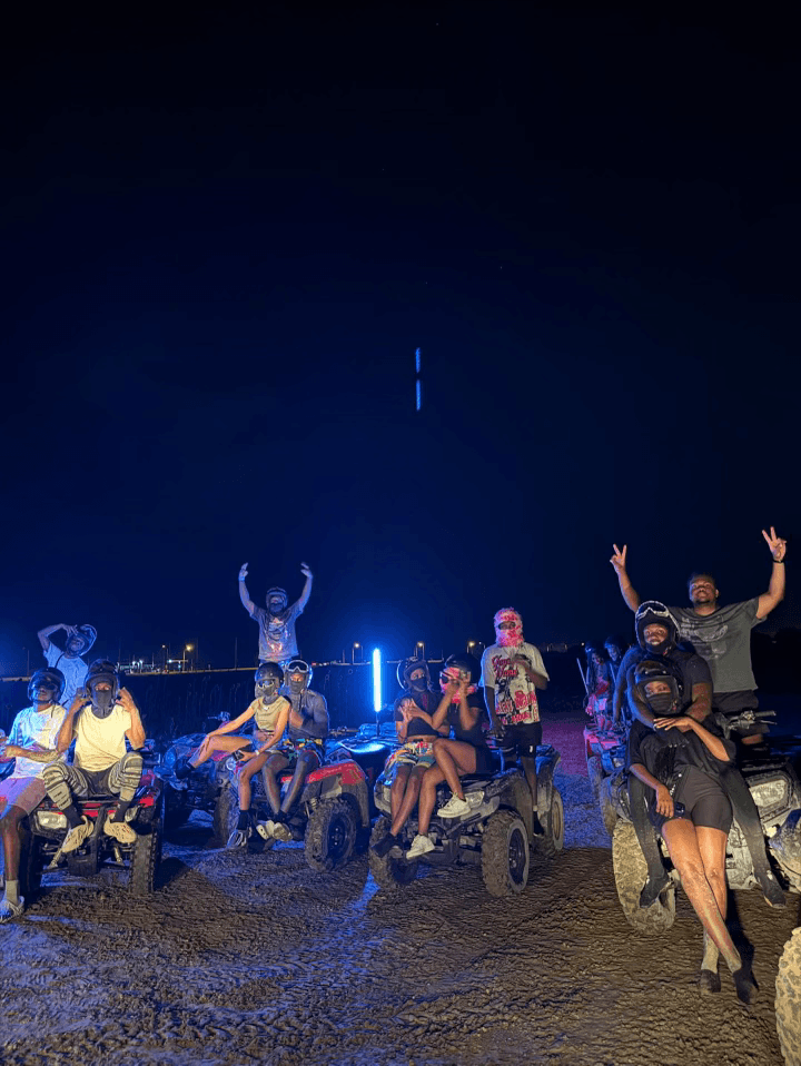 Nighttime group ATV ride on beach with LED lights and riders