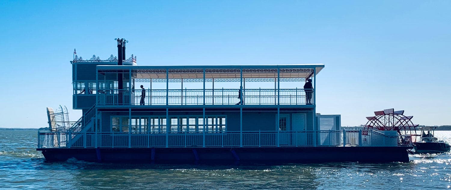 Double-deck river ferry on calm blue water under clear sky