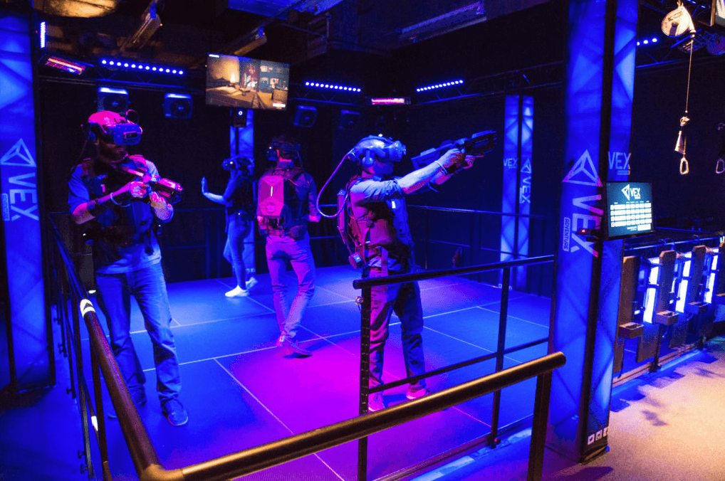 Players in neon-lit VR arena engaging in multiplayer virtual combat