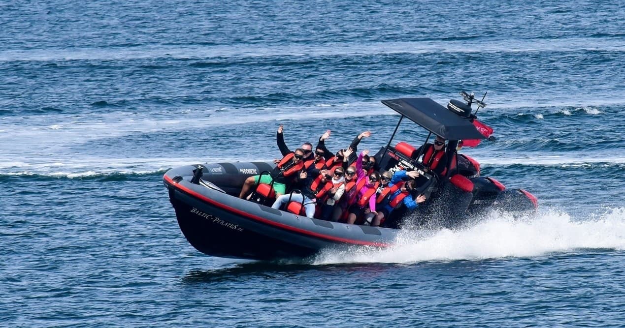 Action RIB tour cutting through blue Baltic sea with excited passengers