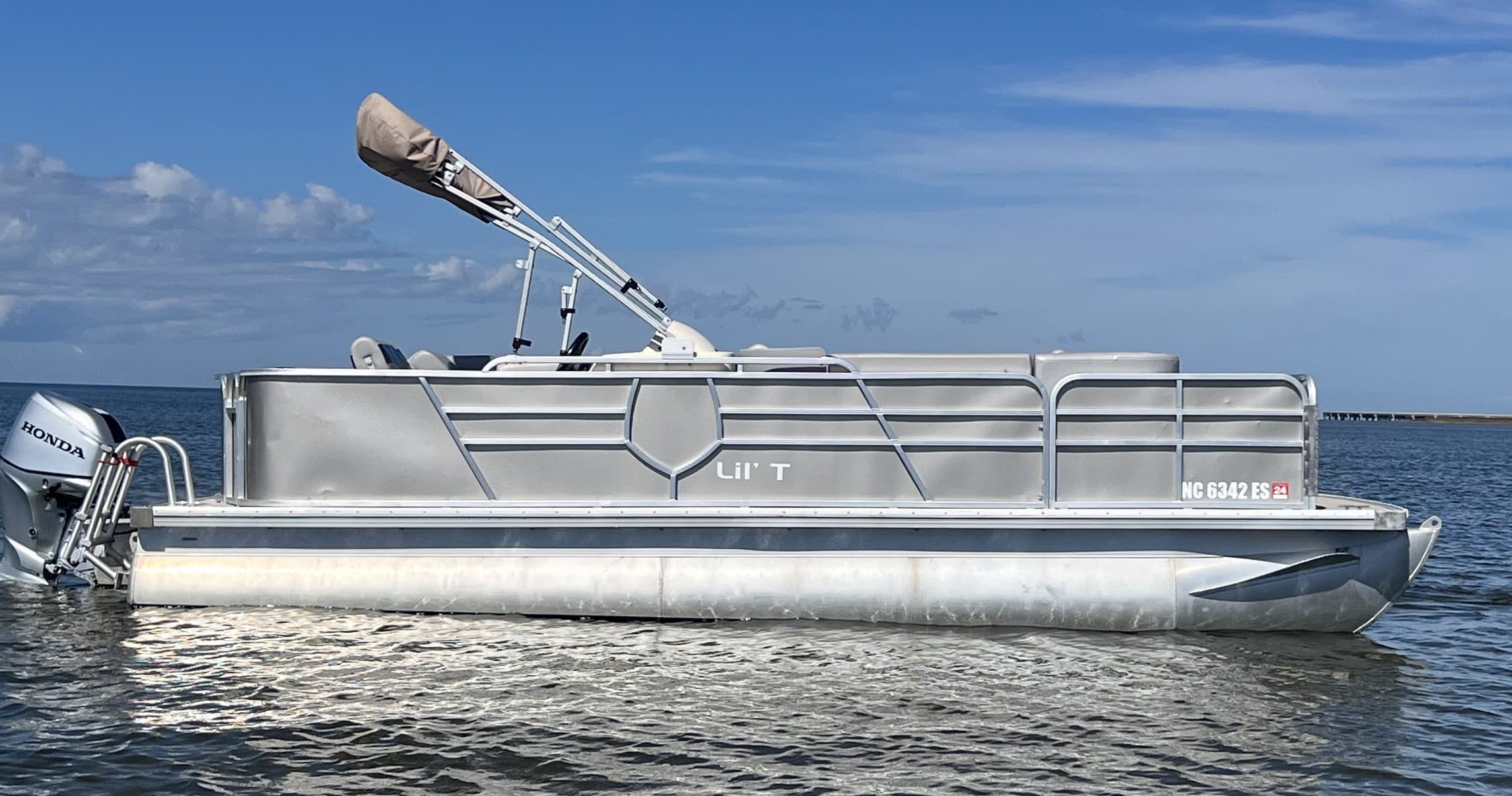 Silver pontoon boat cruising along open blue ocean skyline