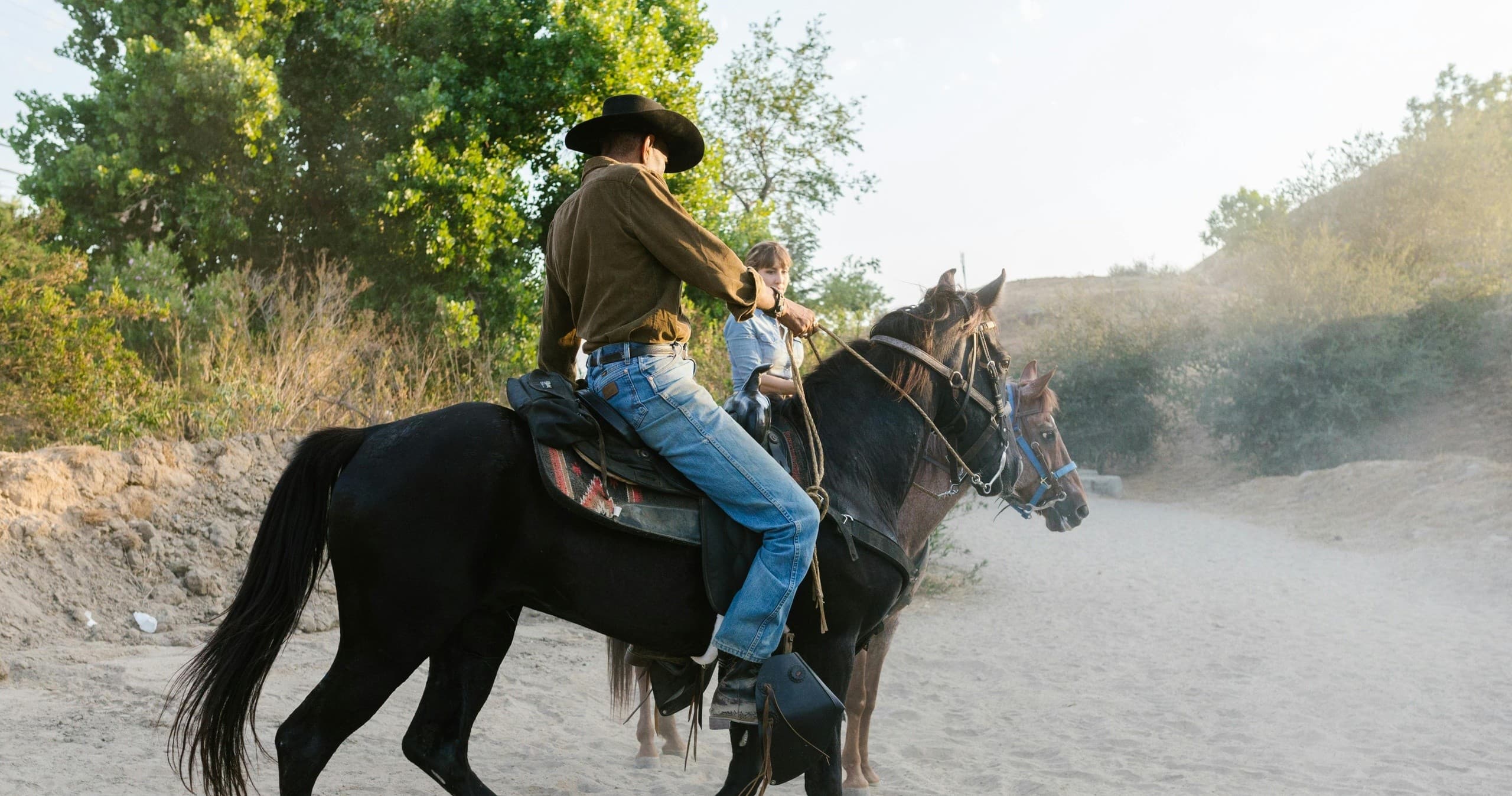 Cowboy galloping on dusty trail during Western horse ride