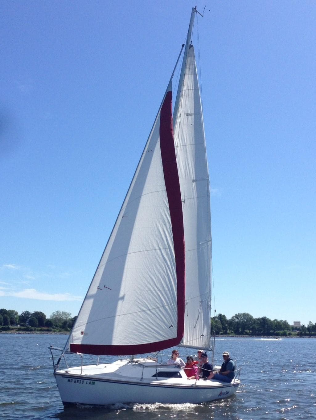 Sailboat under full sail on sunny bay, crew enjoying coastal cruise