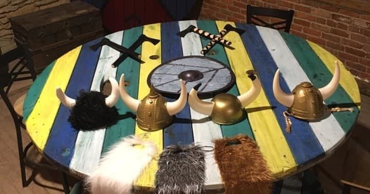 Viking helmets and furs on colorful table inside axe-throwing venue