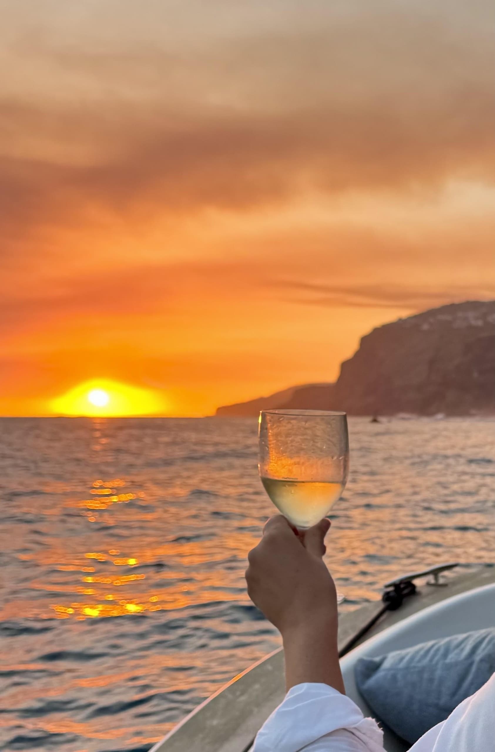 Hand holding wine glass on boat during Madeira sunset cruise