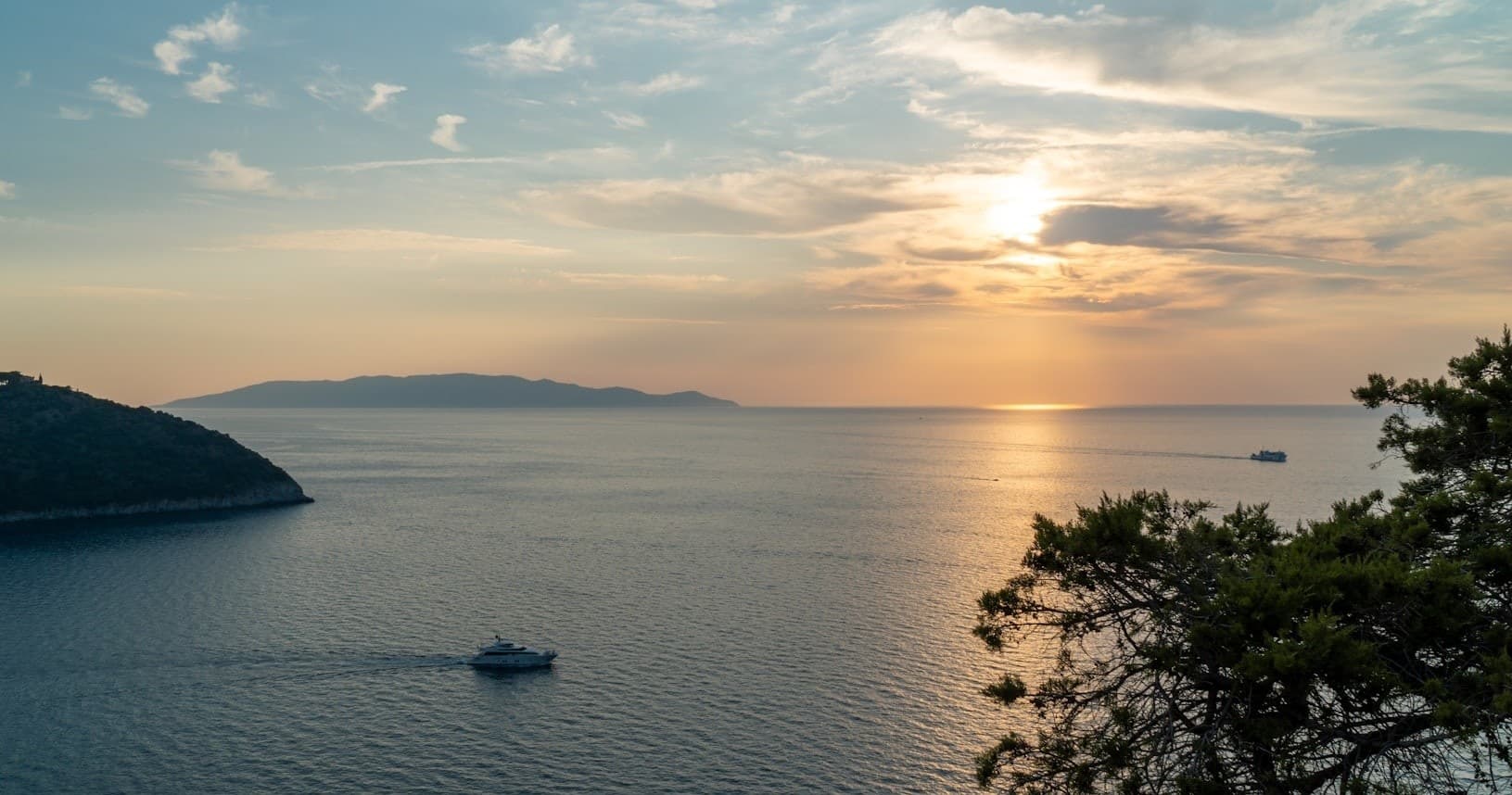 Sunset cruise over calm Mediterranean bay with small boat