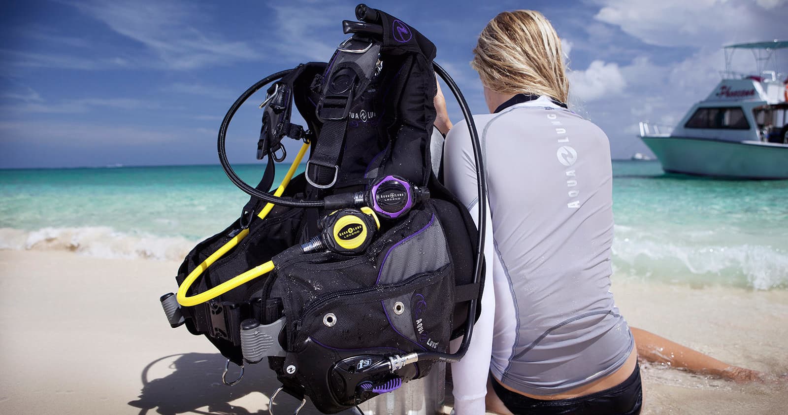Diver preparing gear on tropical sandy beach beside boat