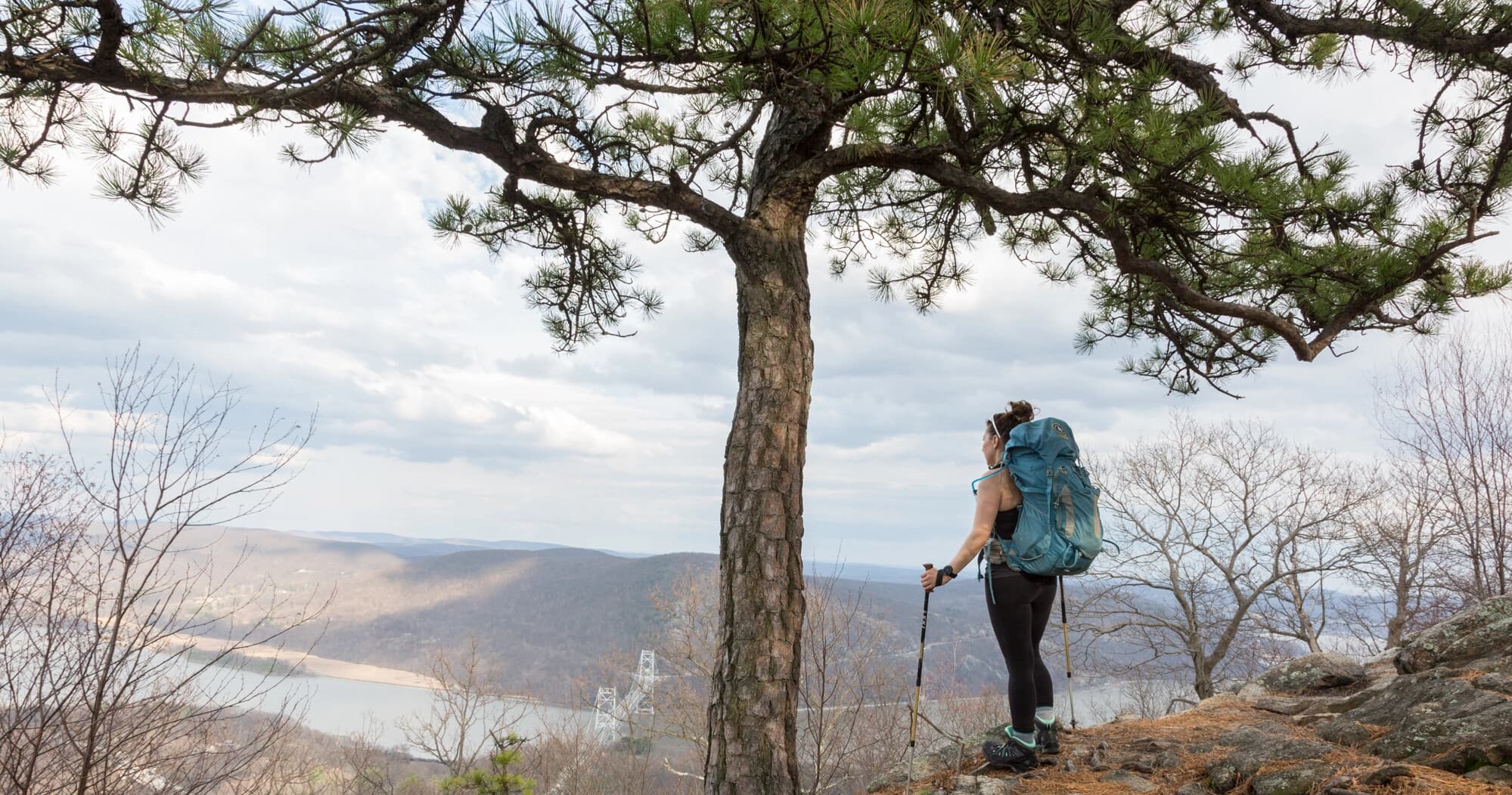 Solo hiker on ridge overlooking river valley at scenic overlook