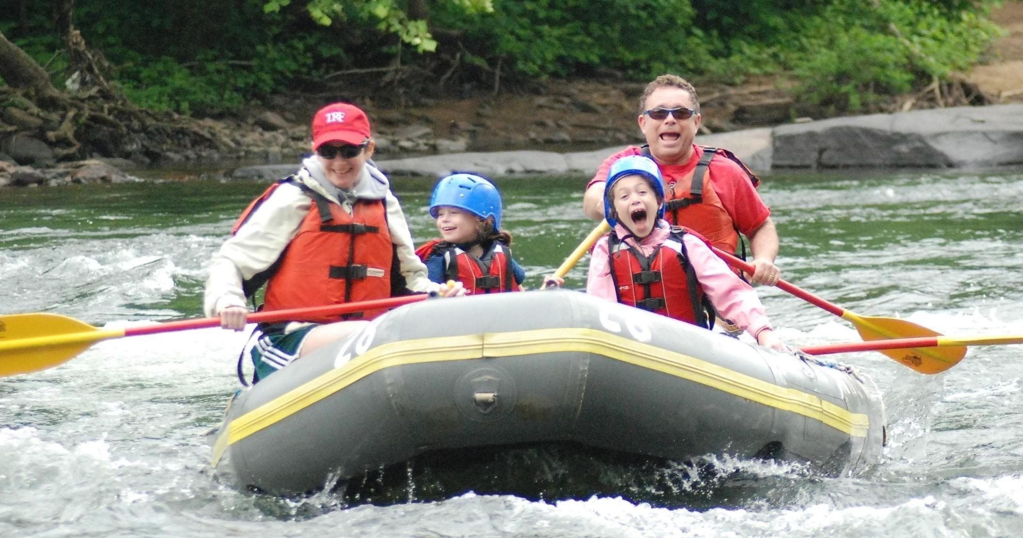 Whitewater rafters navigating fast river rapids in forest