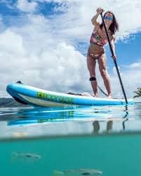 Standup paddleboarder balancing on turquoise tropical ocean water