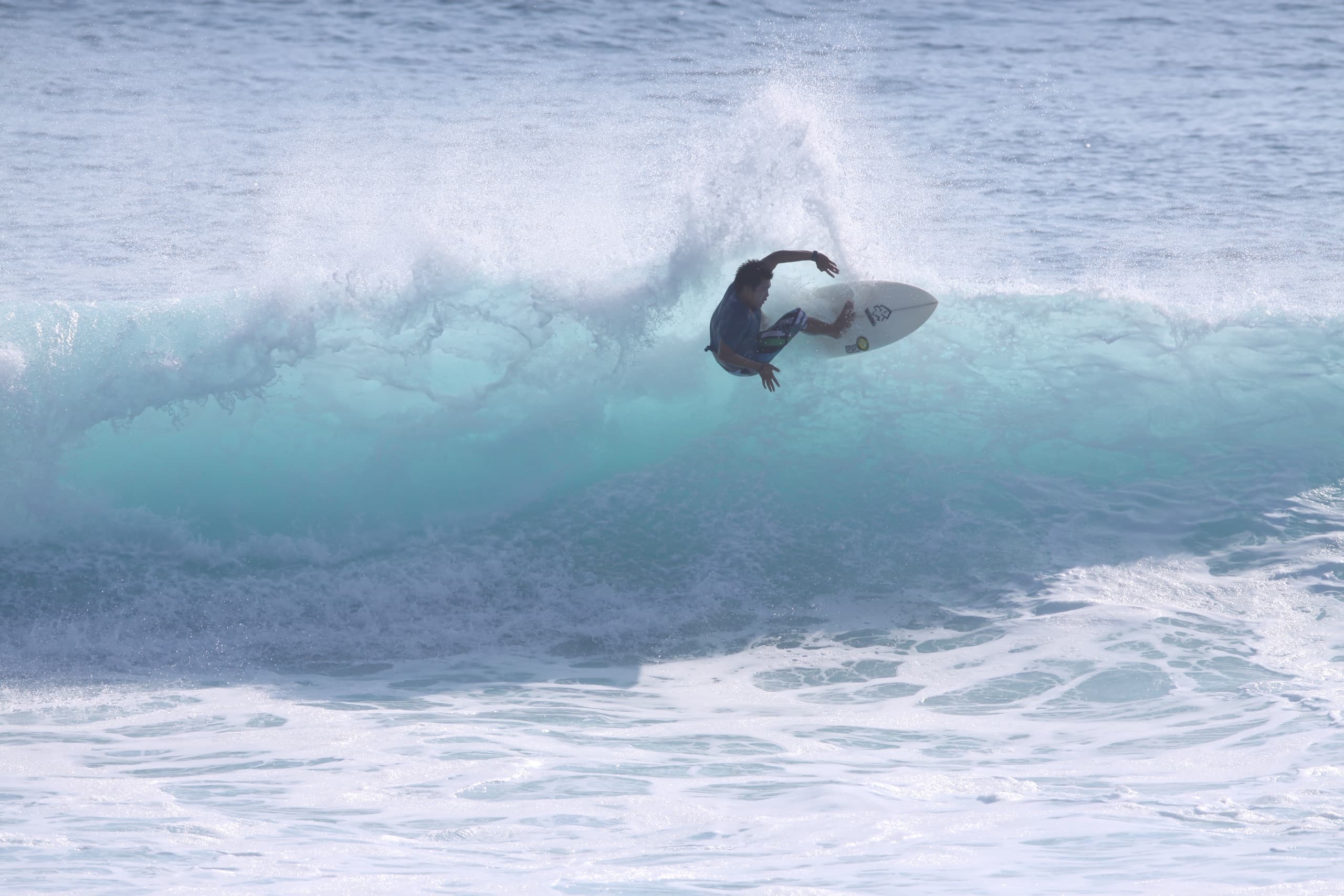Surfer emerging from barrel on turquoise wave at North Shore beach