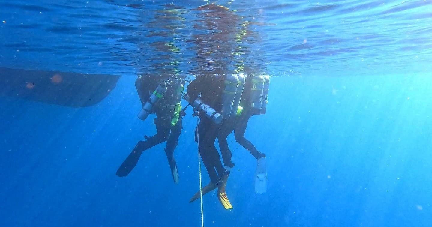 Scuba divers at surface preparing to descend in open ocean