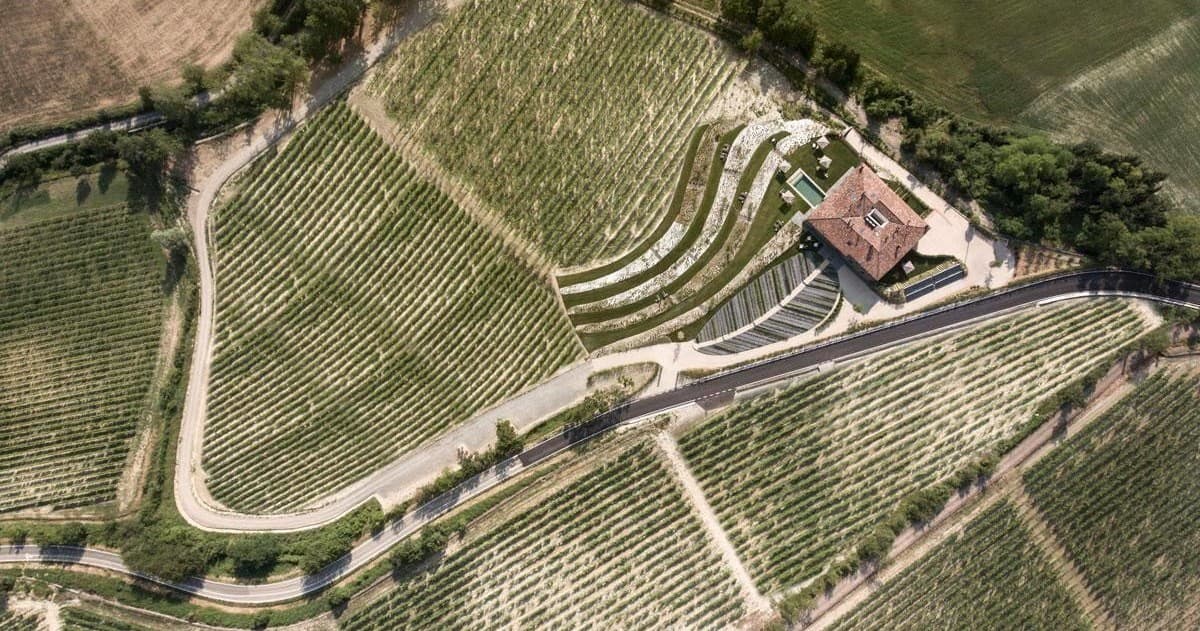 Aerial view of rolling vineyard hills and farmhouse in Tuscany