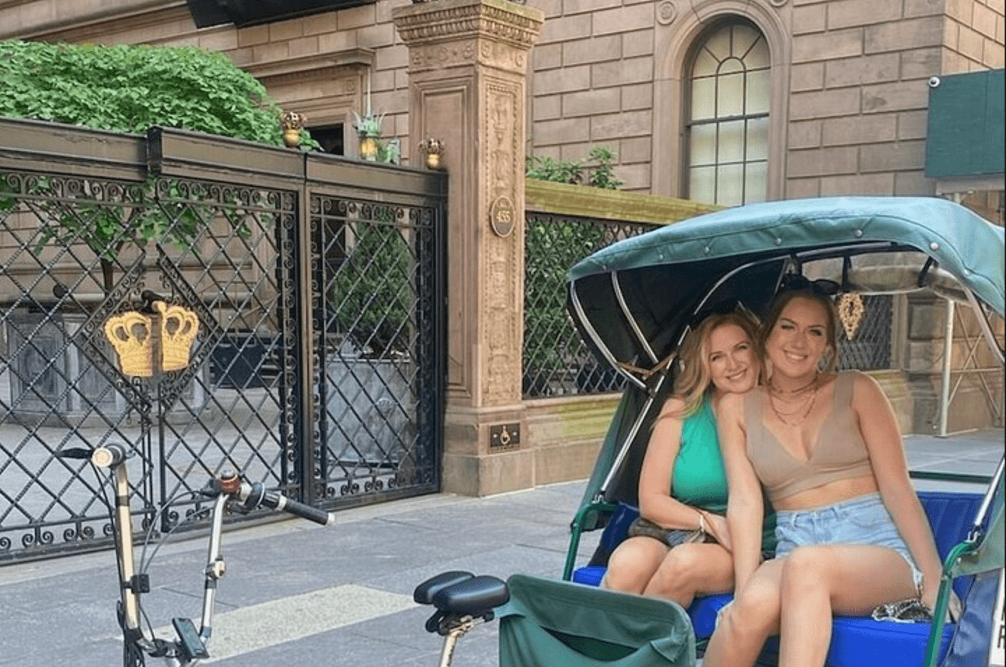 Two women seated in pedicab outside Manhattan brownstone, NYC
