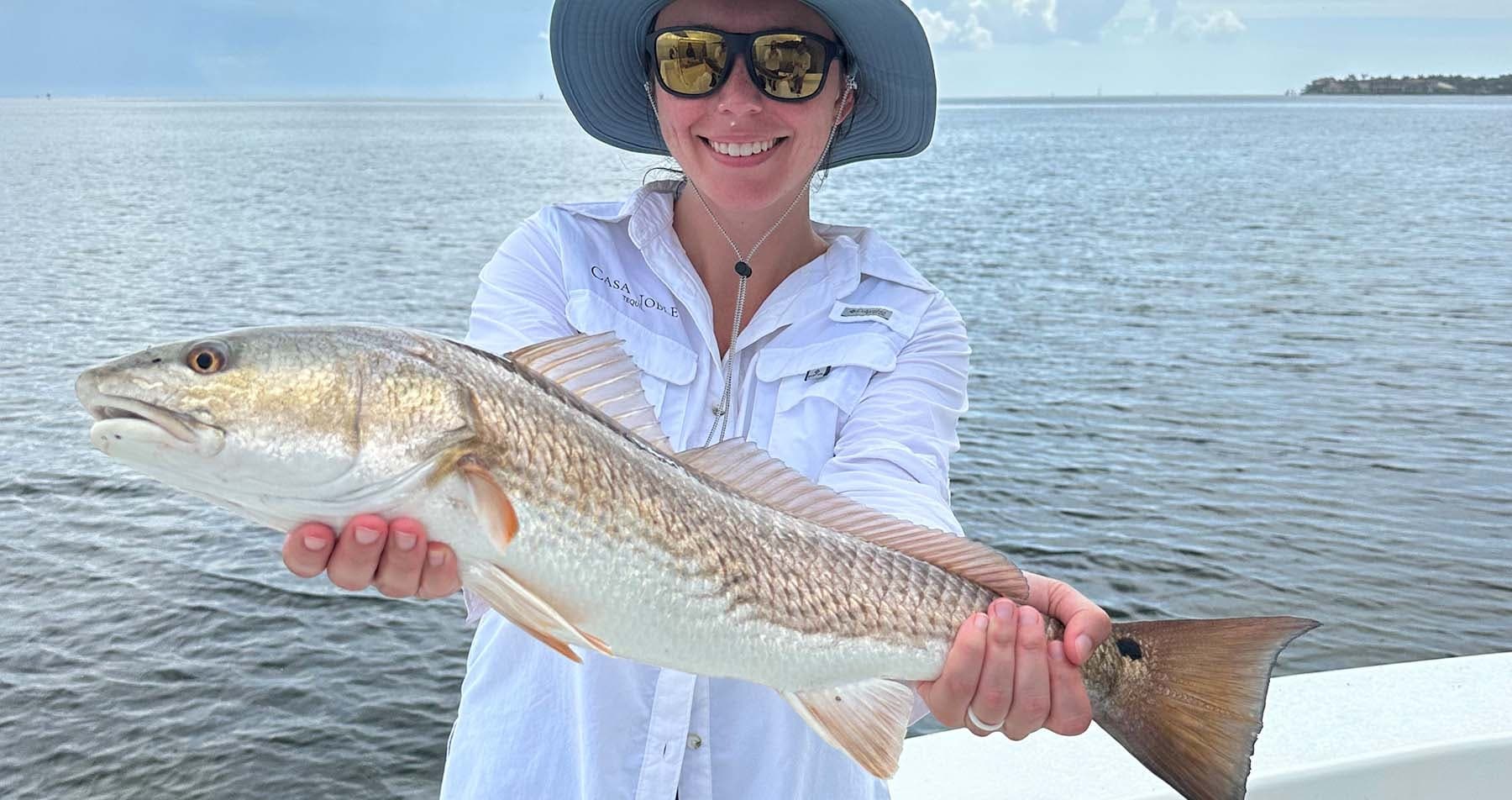 Angler holding redfish on deck with coastal flats horizon