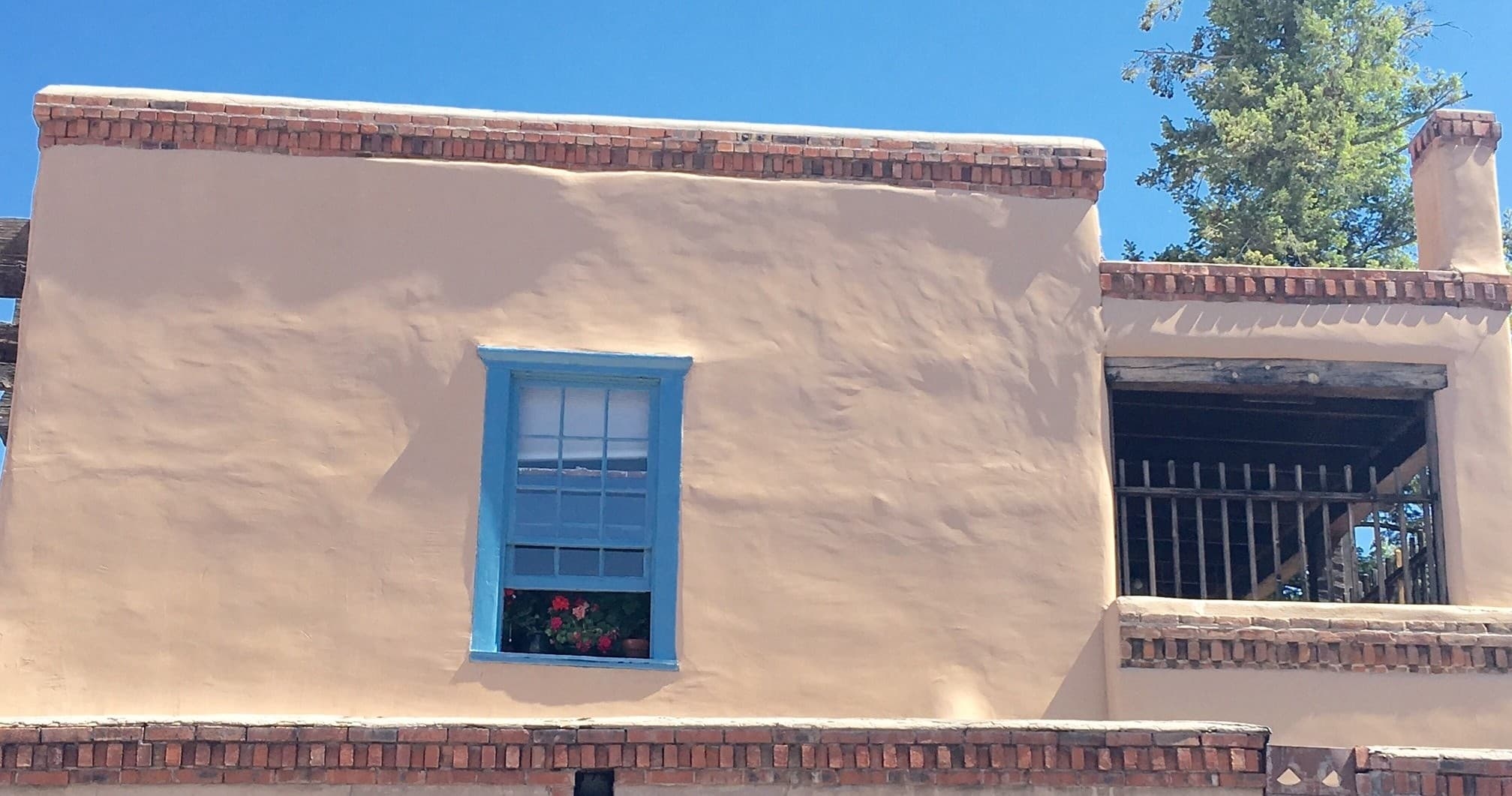 Stucco historic house facade with blue window on Santa Fe walking tour