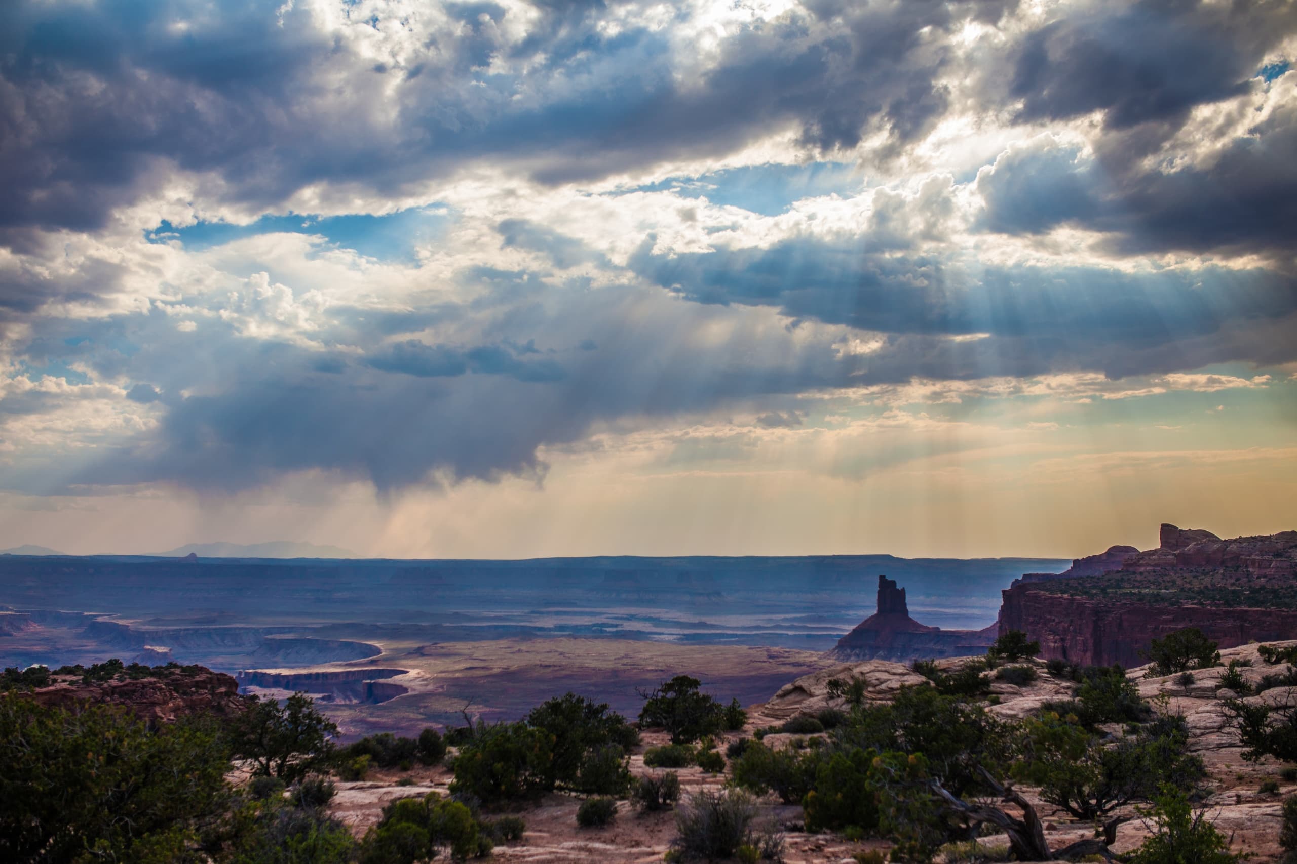 Storm clouds over vast canyon landscape with layered rock formations