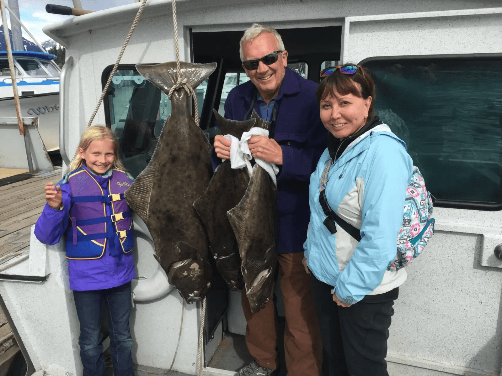 Family posing with caught halibut on dock after Alaskan charter