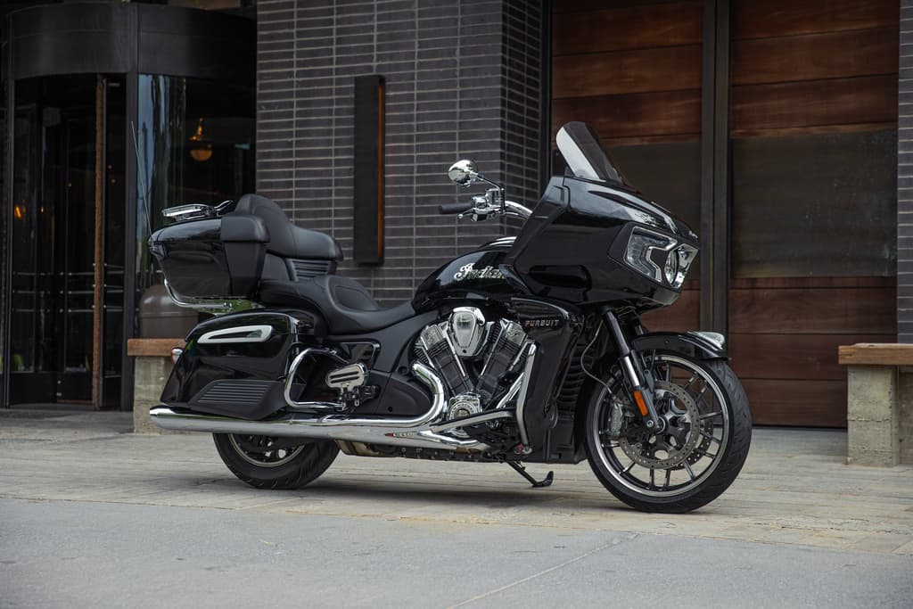 Black touring motorcycle parked outside modern hotel entrance