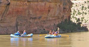 Rafts drifting near towering canyon walls on peaceful river