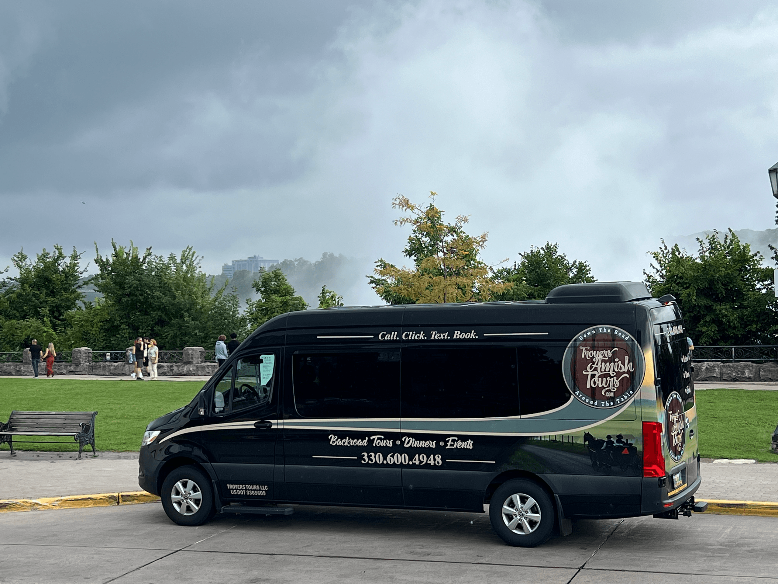 Troyer's Amish Tours van parked by park under cloudy sky