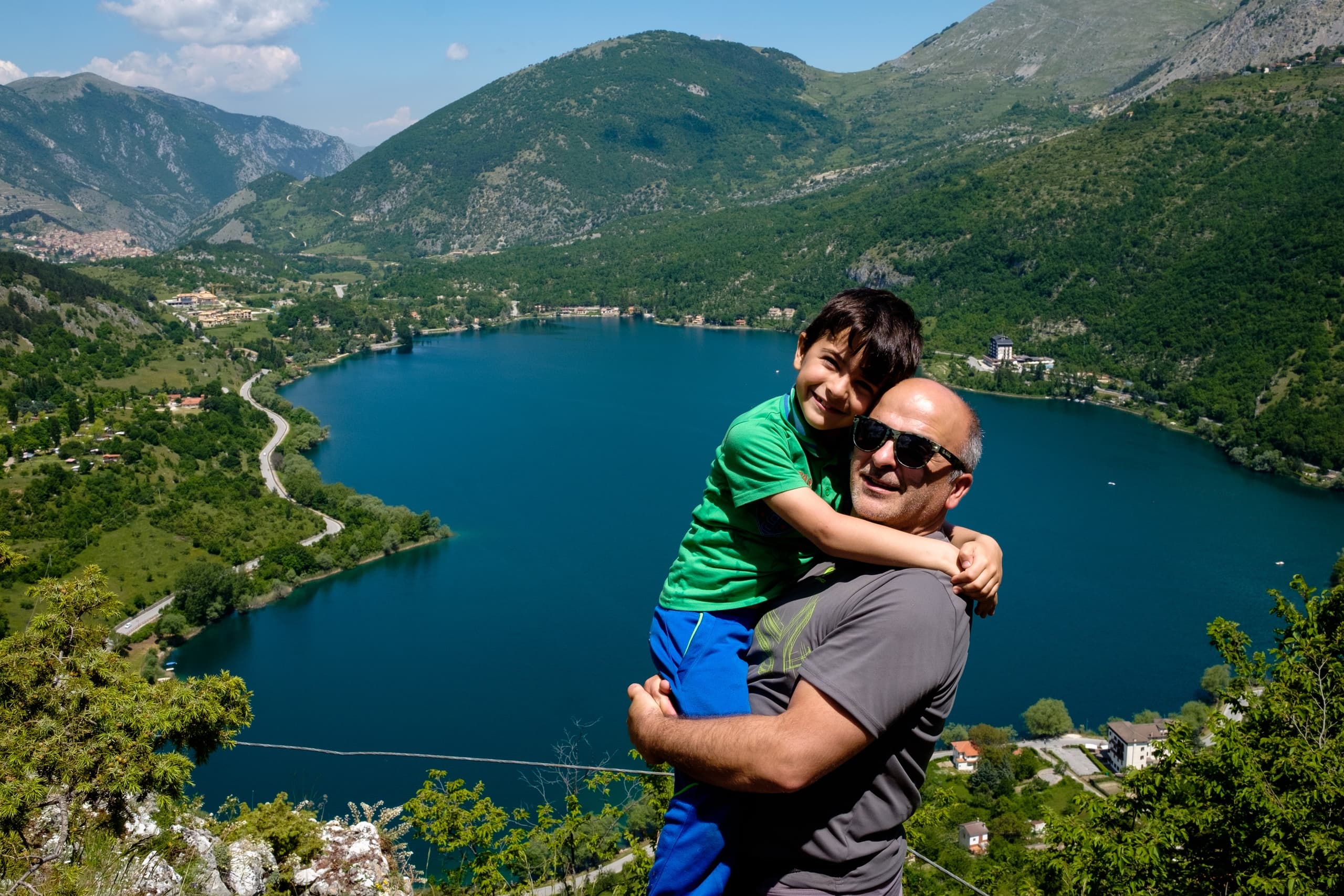 Father and child hiking at mountain lake overlook, scenic vista