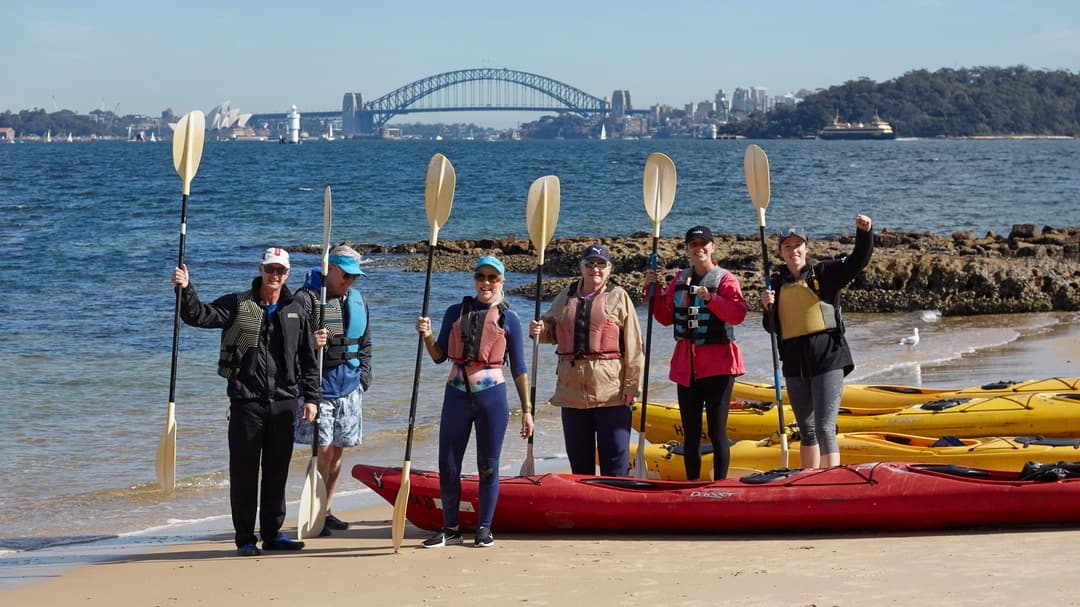 Group beach kayaking launch with Sydney Harbour Bridge backdrop