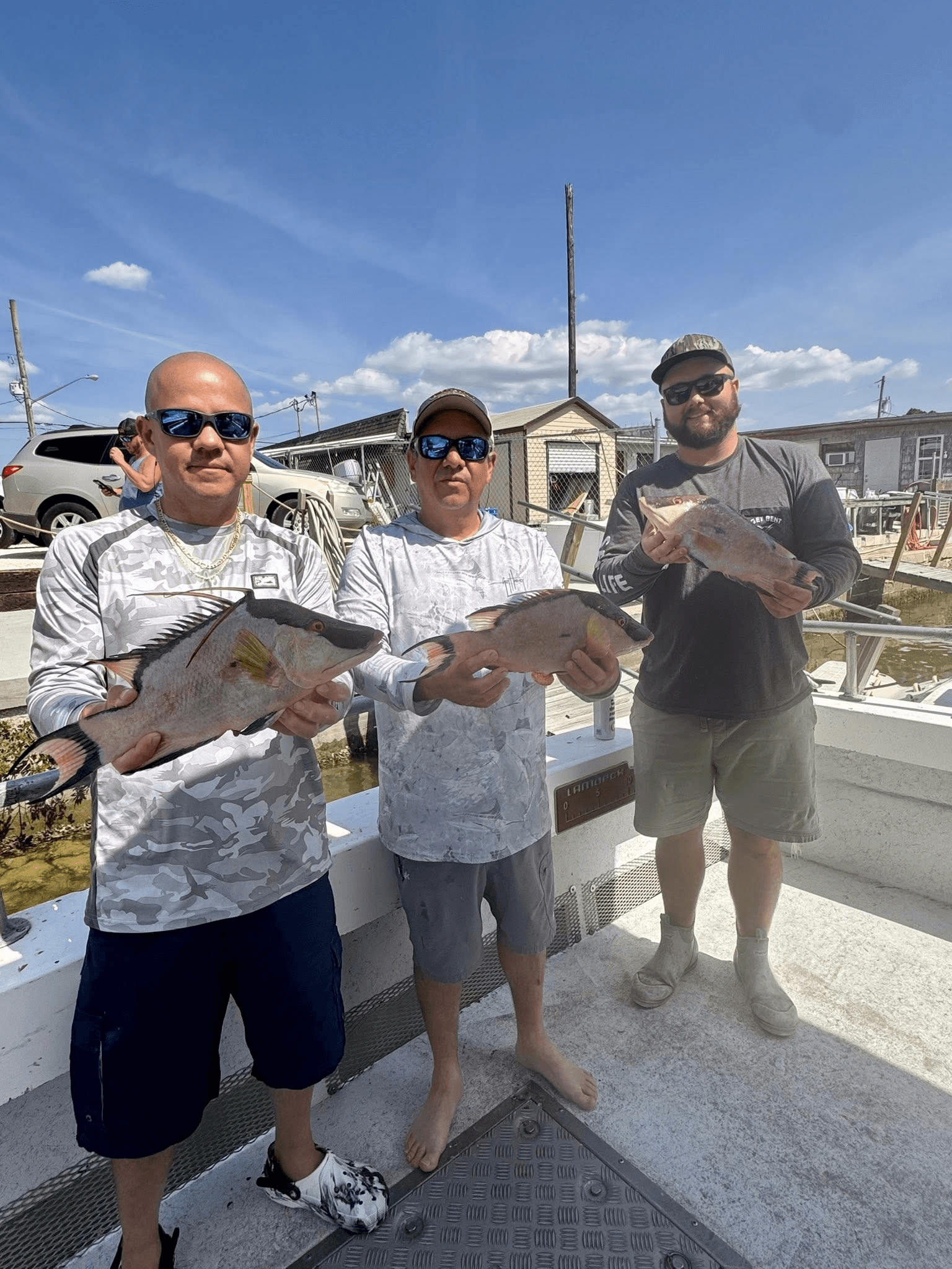 Three anglers posing with fish at marina after offshore trip