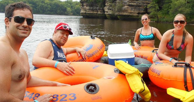Friends tubing together on river in bright orange inner tubes