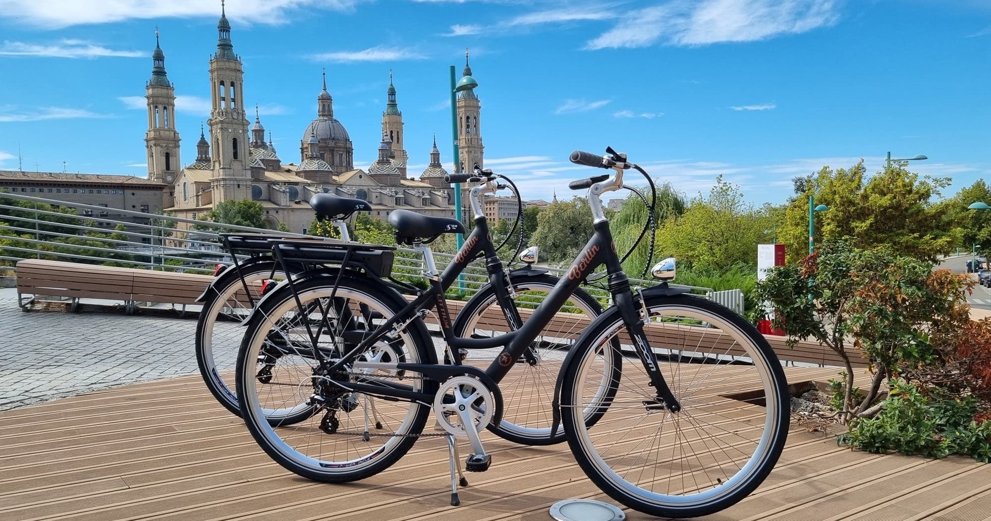 Bicycles parked by Ebro river with Zaragoza cathedral backdrop