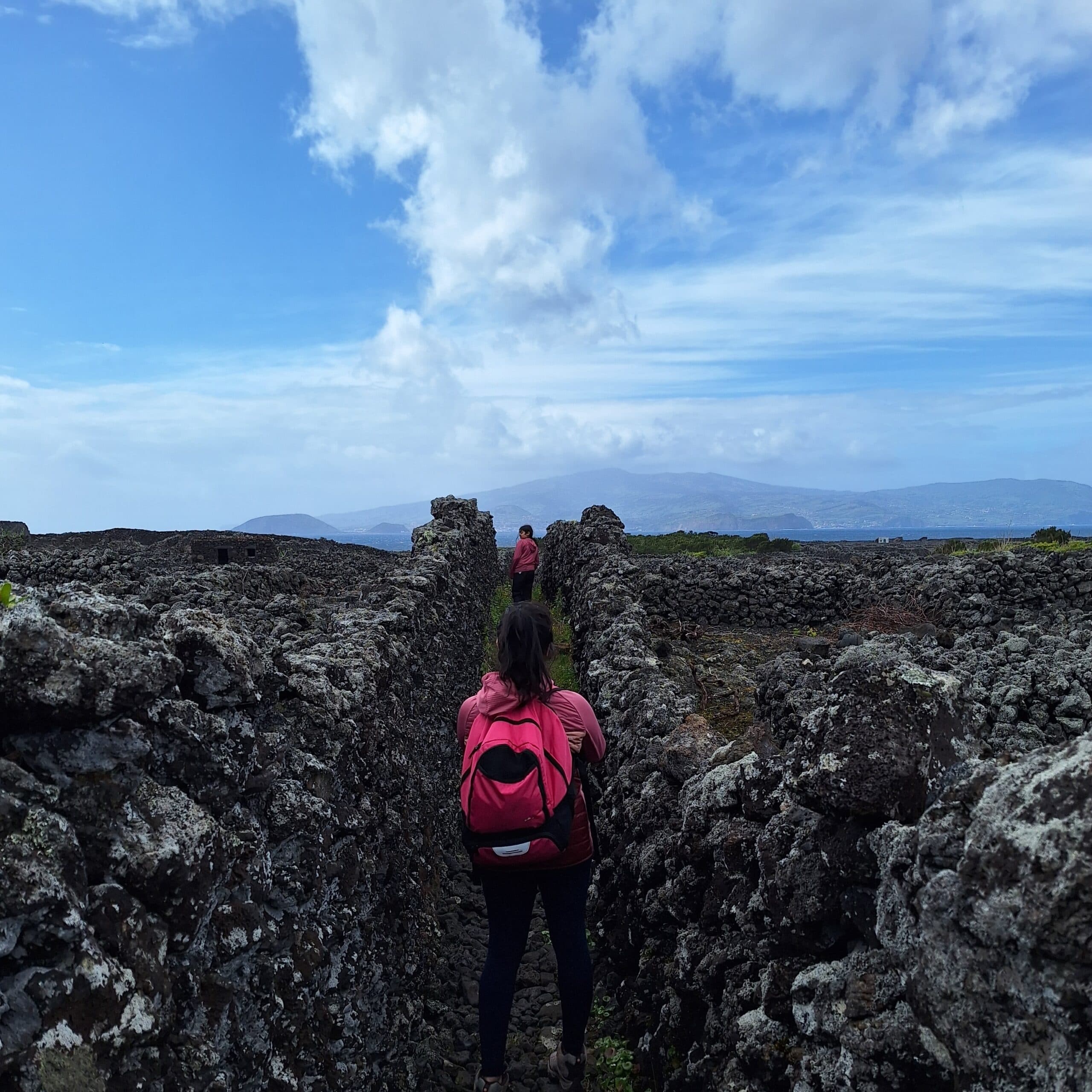 Hiker walking lava rock fissures with backpack on volcanic trail