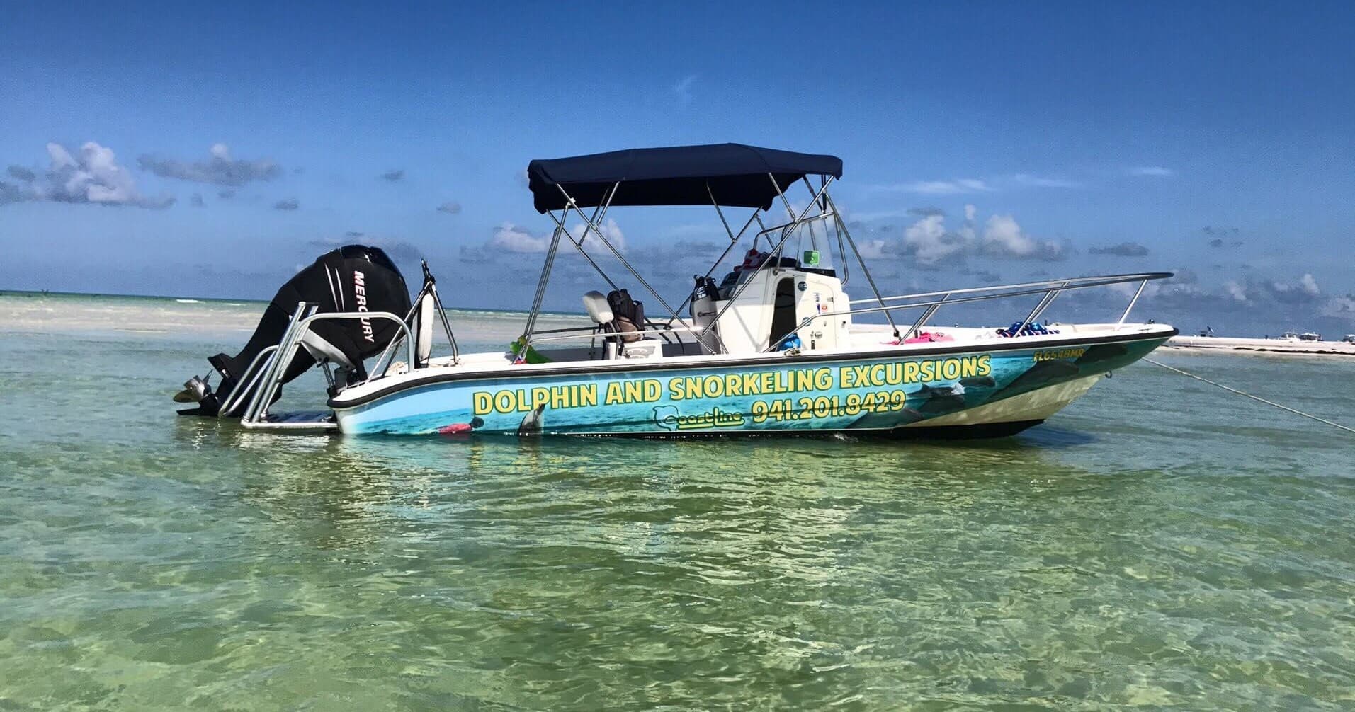 Tour boat anchored in clear shallow water, coastal snorkeling excursion