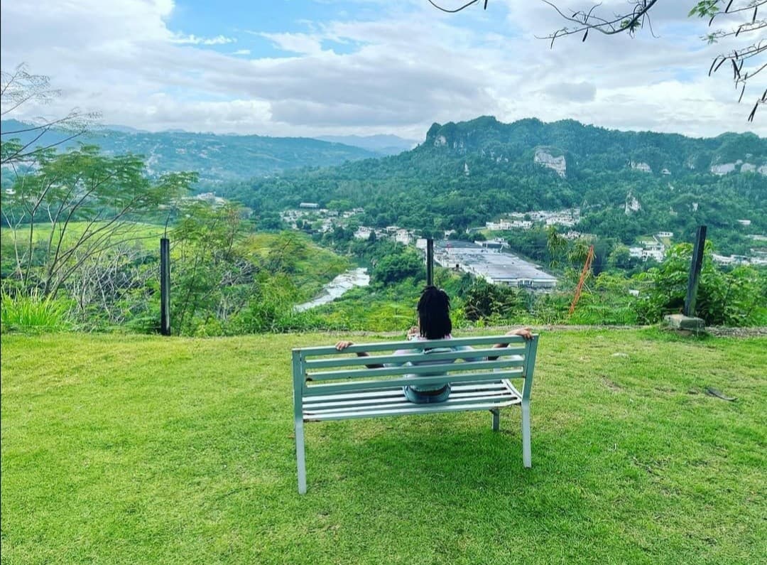 Solo traveler seated on bench admiring mountain view, Puerto Rico