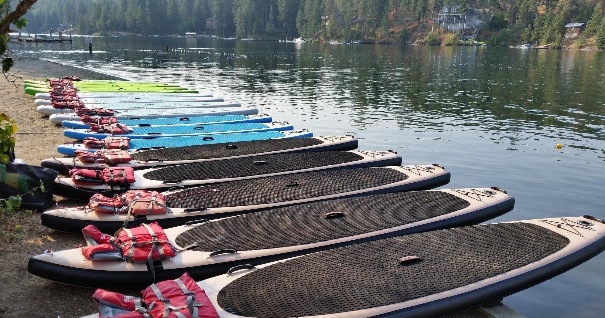 Row of paddleboards docked along reflective mountain lake shore