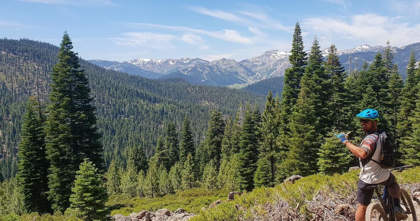 Mountain biker overlooking Tahoe alpine forest and distant peaks