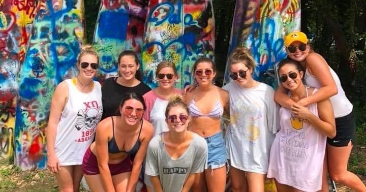 Friends posing by colorful graffiti near wooded outdoor spot