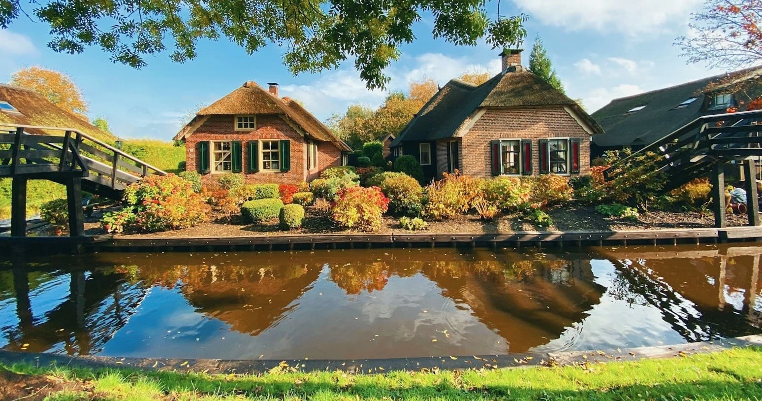Scenic thatched cottages by canal with reflections, countryside boat