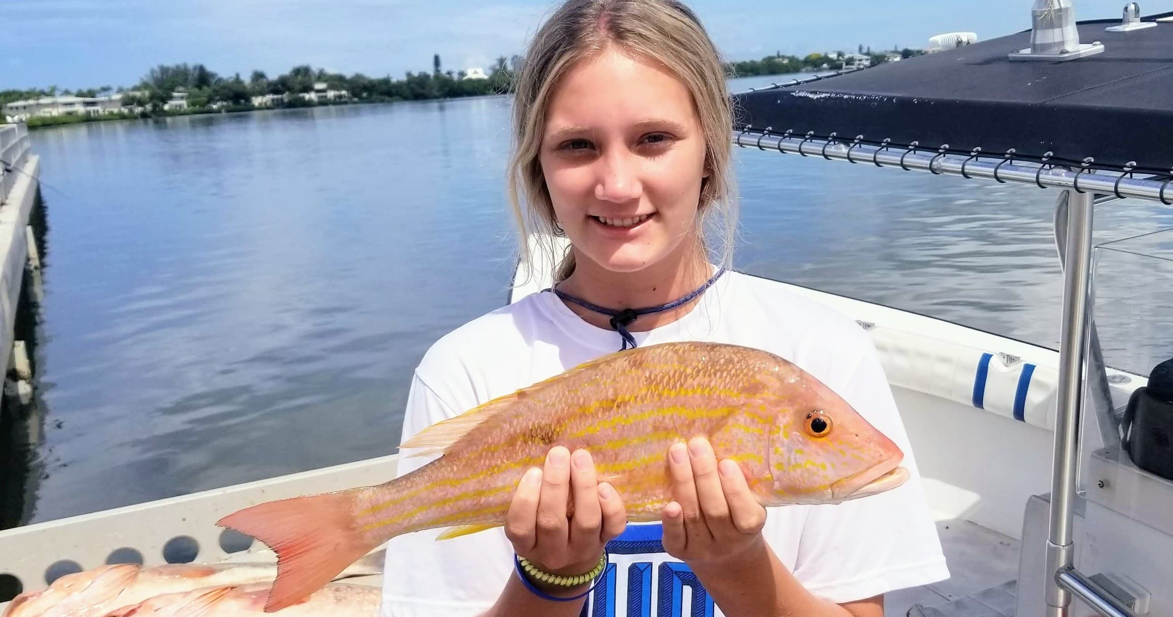 Young angler holding yellowtail on charter boat near marina