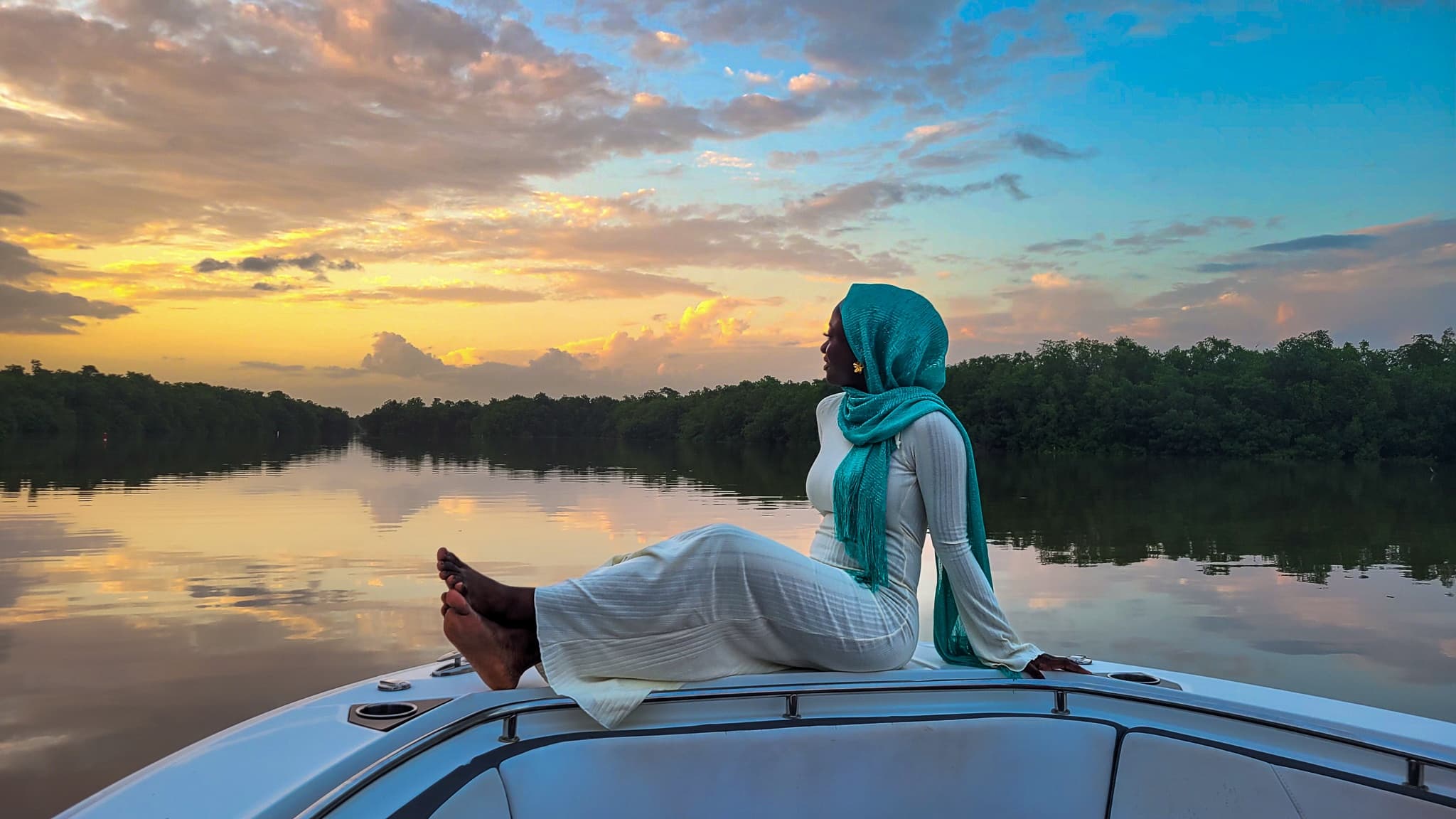Person reclining on boat bow at sunset over calm lake