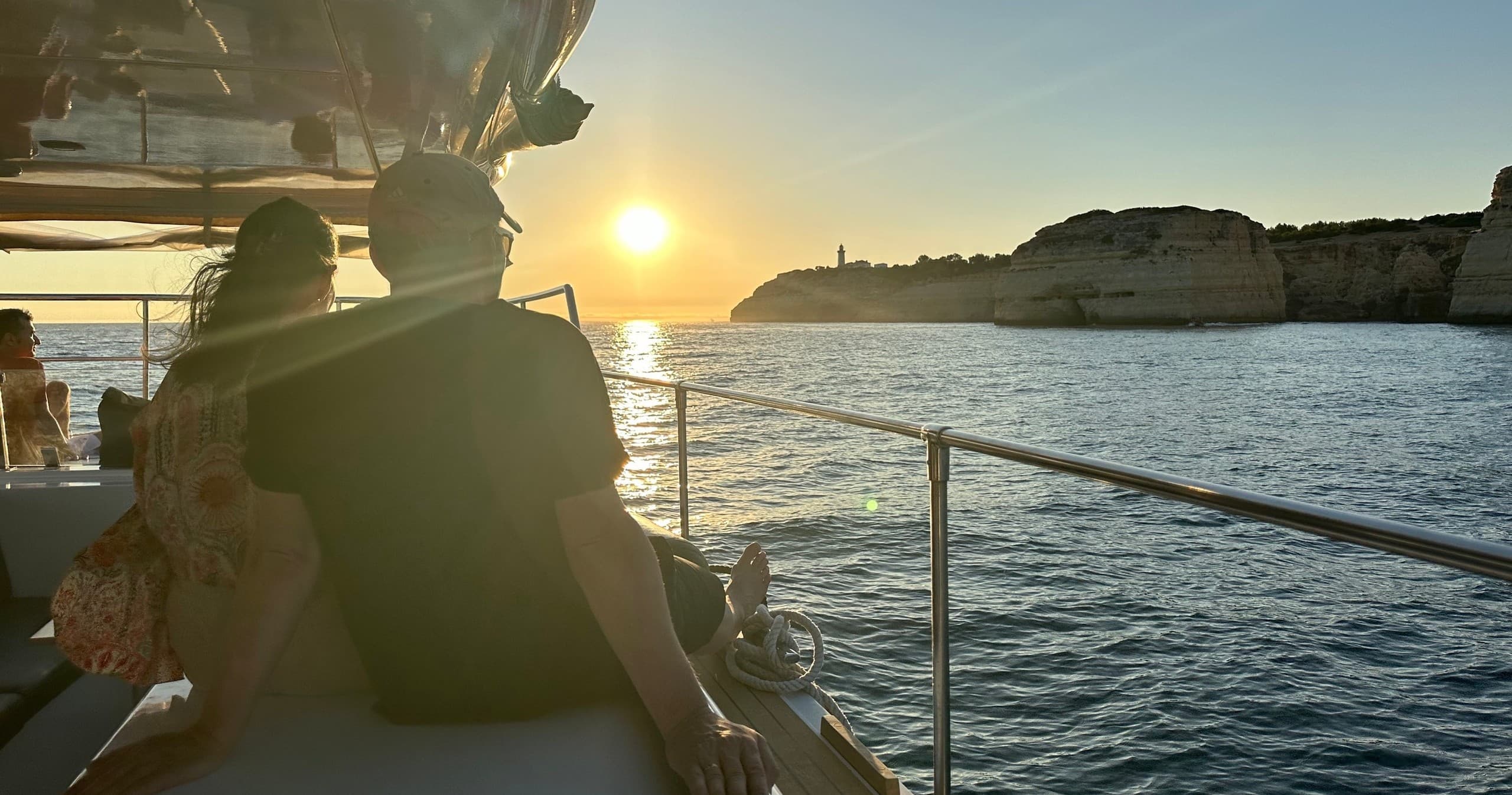 Couple watching ocean sunset from tour boat deck at dusk
