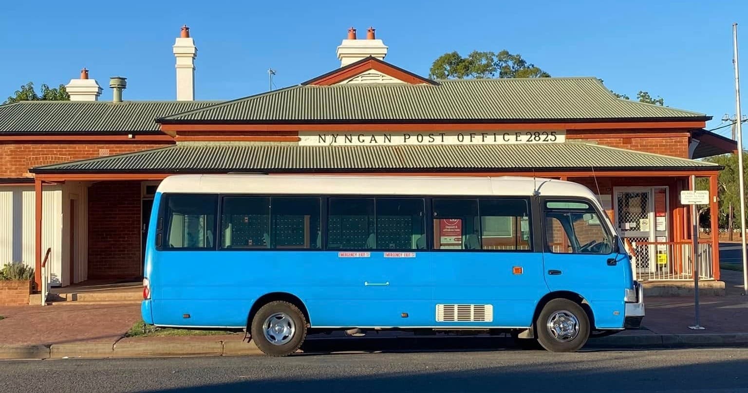Side view blue shuttle outside classic town hall under clear sky