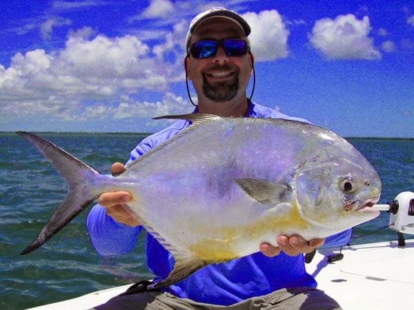 Angler holding large gamefish on a charter boat in coastal waters