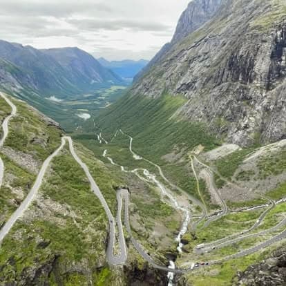 Motorbikes on steep winding mountain pass through green valley