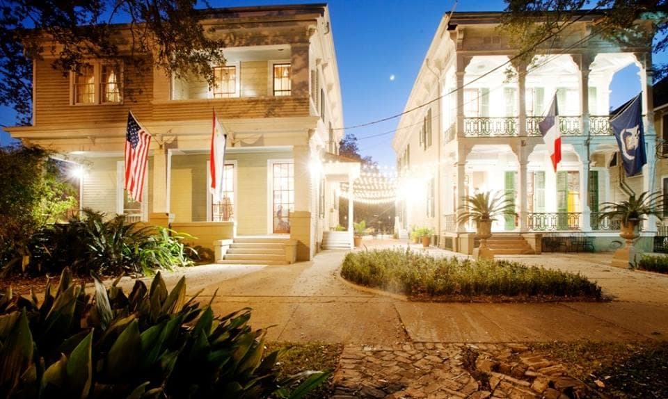 Historic inn exterior at dusk with lit walkway and flags